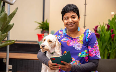 Naveena wearing a purple top while holding her dog 